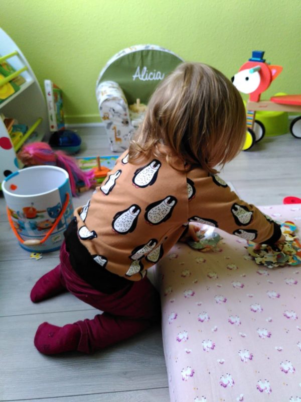 Enfant qui joue dans sa chmabre avec un sweat avec motifs pinguoins